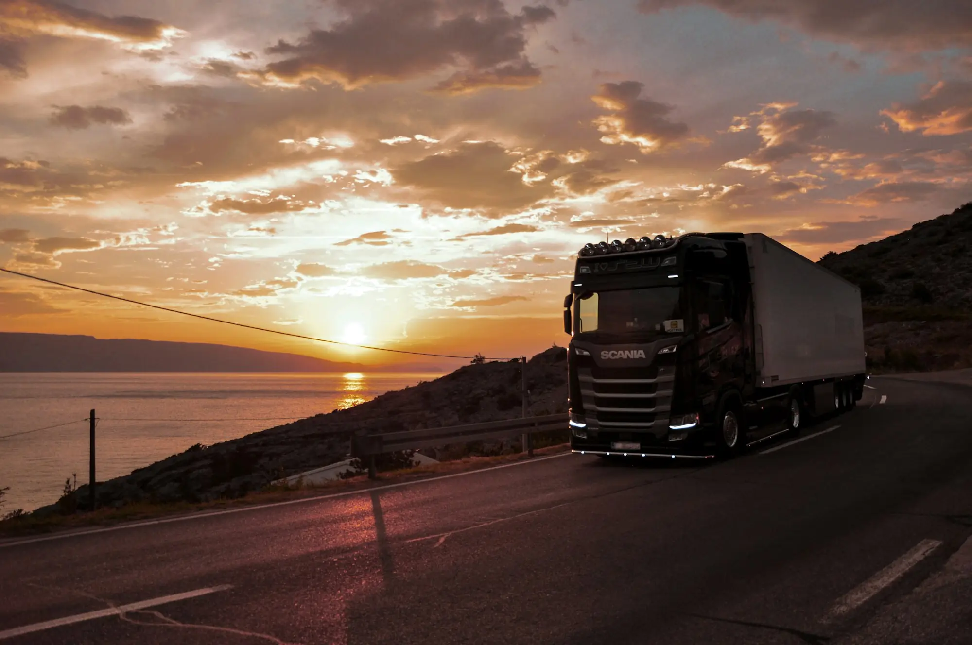 Camión en una carretera de costa al atardecer